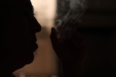 Close-up of silhouette person smoking indoors