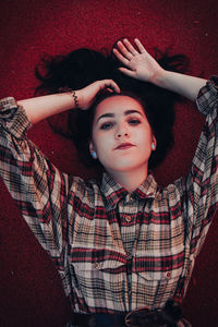 Portrait of young woman laying on the ground with red background 