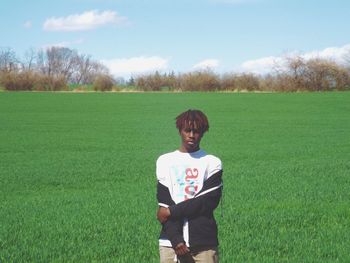 Portrait of young man standing on grassy field