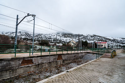 Road by buildings against sky during winter