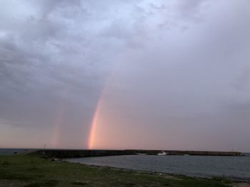 Scenic view of rainbow over sea against sky