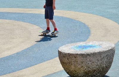 Low section of boy standing on skateboard at playground during sunny day