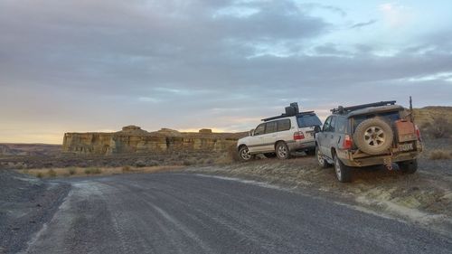 Cars on road against cloudy sky