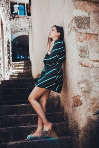 Side view full length of young woman standing on steps