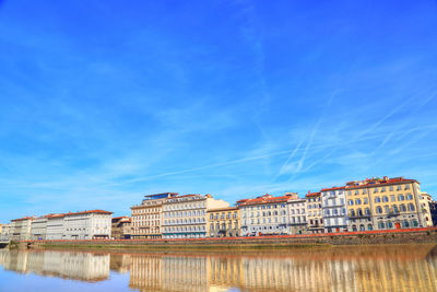 Reflection of buildings in lake against blue sky