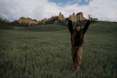 Rear view of woman standing on field against sky