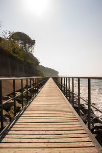 Wooden footbridge over sea against clear sky