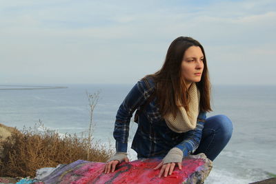 Young woman looking away against sea and sky