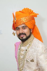 Portrait of smiling man in traditional clothes standing against wall