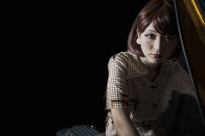 Portrait of beautiful young woman riding vintage motor scooter against black background