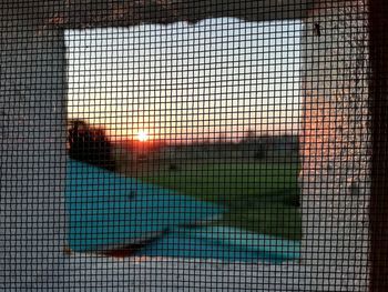 Close-up of swimming pool against window at sunset