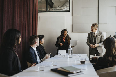 Female entrepreneur discussing with male and female coworkers during business meeting at office