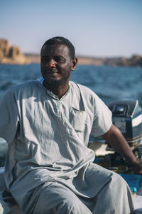 Portrait of man sitting in sea against sky