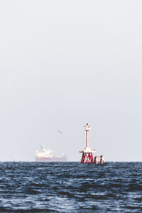 Boat sailing in sea against clear sky