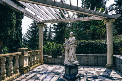 Statue standing by tree against sky