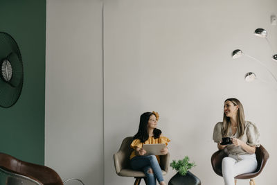 Young woman looking at camera while sitting against wall