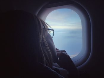 Close-up of airplane window and woman looking outside