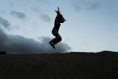 Low angle view of man jumping in desert