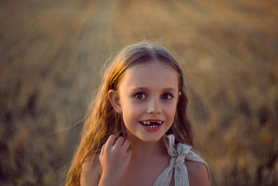 Portrait of a child girl without front teeth from above standing on a field at sunset