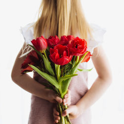 Close-up of woman holding rose bouquet against white background