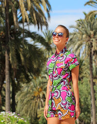 Young woman wearing sunglasses standing against trees