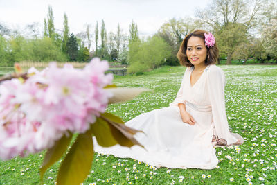 Woman looking away while sitting on lawn