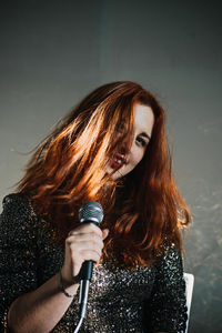 Portrait of redhead female singer woman in sparkly evening dress holding microphone. singer at