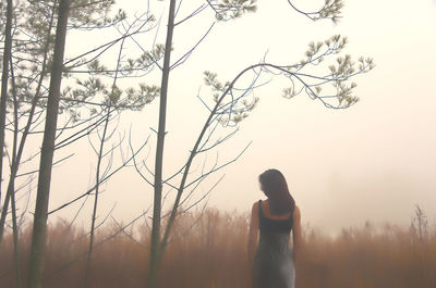 Side view of woman standing on field against sky