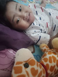 Portrait of smiling girl lying on bed at home