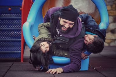 Happy father with children in slide at playground