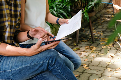 Midsection of man holding paper while sitting on floor