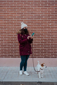 Woman with dog against brick wall