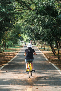 Rear view of man riding bicycle on road