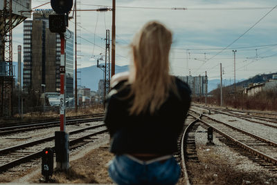 Rear view of woman standing on railroad track