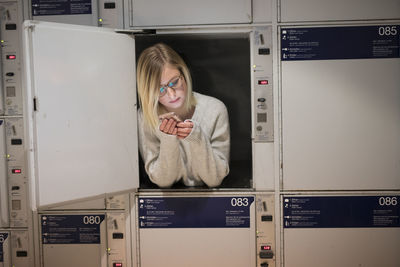 Young woman using phone in locker