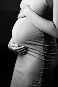 Midsection of woman standing against black background