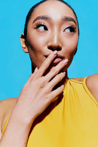 Close-up of young woman against blue background