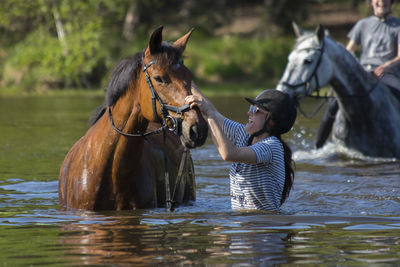 Side view of woman with horse standing in lake