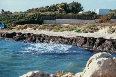 Scenic view of rocks by sea against sky