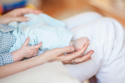 Midsection of mother touching baby feet relaxing on lap