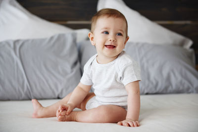 Smiling baby girl sitting on bed at home