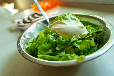 Rinsed green lettuce with sour cream in a silver bowl