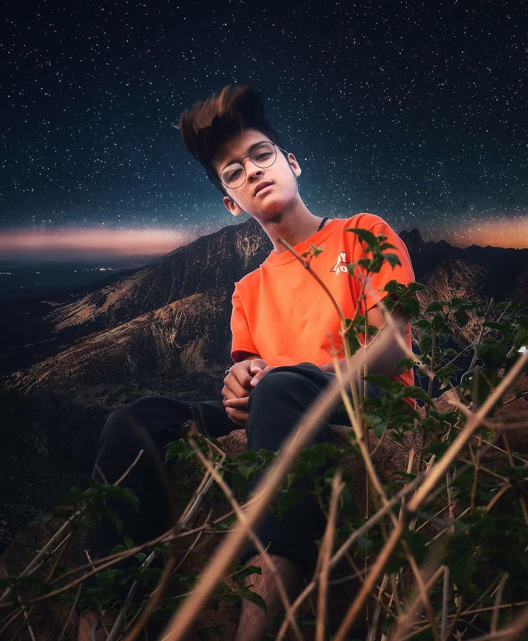 one person, night, sky, nature, young adult, star - space, scenics - nature, real people, beauty in nature, leisure activity, field, land, three quarter length, lifestyles, space, sitting, young men, front view, casual clothing, plant, astronomy, outdoors