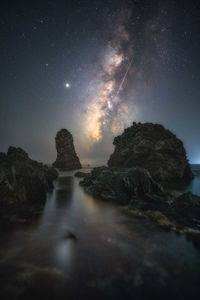 Rock formation in sea against sky at night