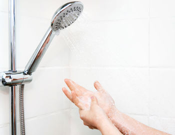 Woman washing hands with soap in shower.