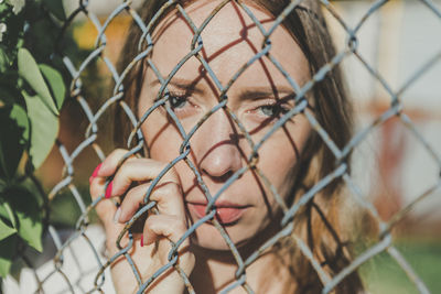 Portrait of man seen through chainlink fence