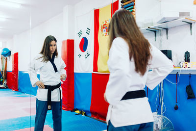 Young woman wearing martial arts dress while standing by mirror