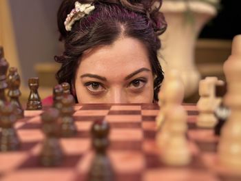 Asian woman looks at camera over chessboard