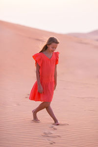 Full length of woman with pink umbrella standing on land