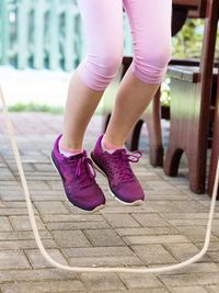 Low section of girl with pink shoes jumping a jump rope 